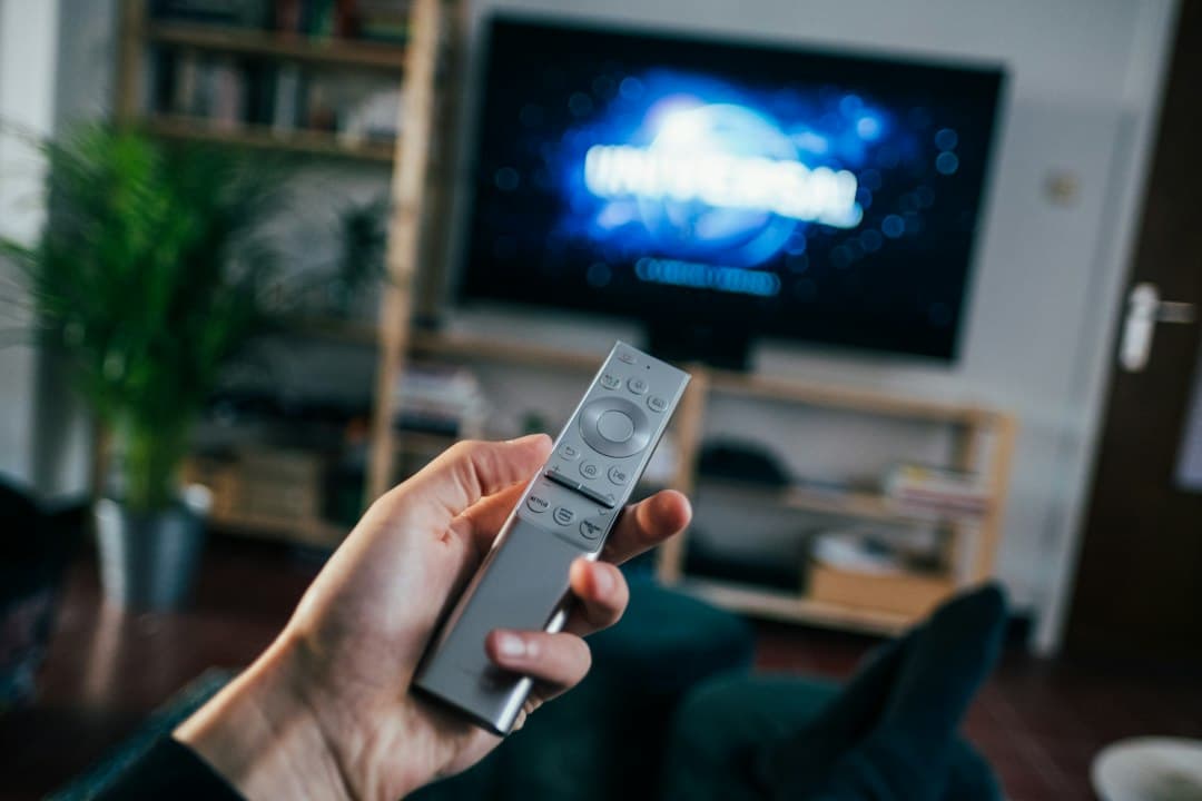 Personne tenant une télécommande devant un téléviseur affichant un message d'erreur